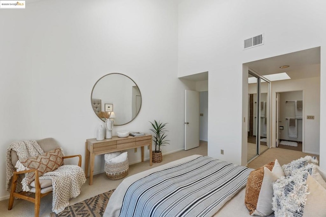 bedroom featuring a closet, light colored carpet, and a high ceiling