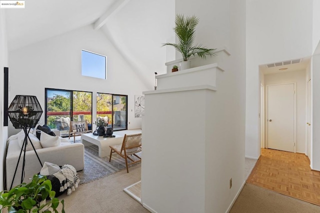 interior space with beamed ceiling, a towering ceiling, and light parquet floors