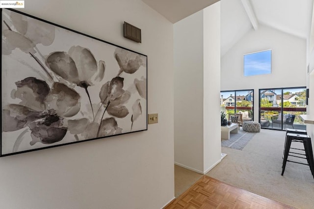 corridor featuring beamed ceiling, light carpet, and high vaulted ceiling