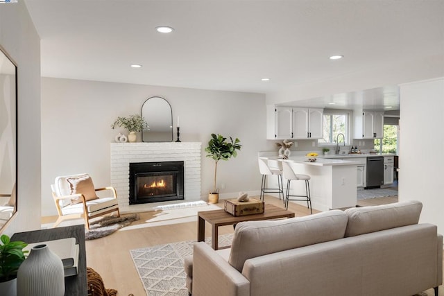 living room with a fireplace, light wood-type flooring, and sink