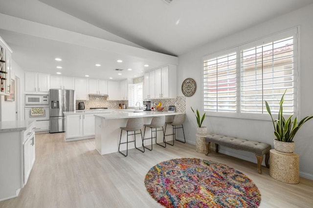 kitchen featuring kitchen peninsula, stainless steel fridge, white microwave, tasteful backsplash, and white cabinets