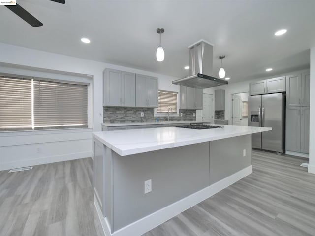 kitchen with appliances with stainless steel finishes, island range hood, sink, decorative light fixtures, and a kitchen island