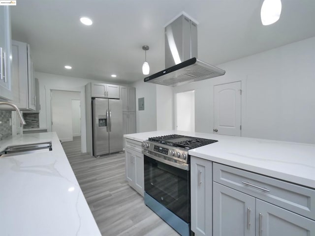 kitchen with island exhaust hood, stainless steel appliances, sink, gray cabinets, and hanging light fixtures