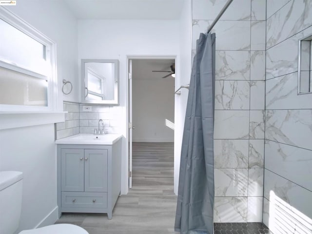 bathroom with a shower with shower curtain, ceiling fan, toilet, and vanity