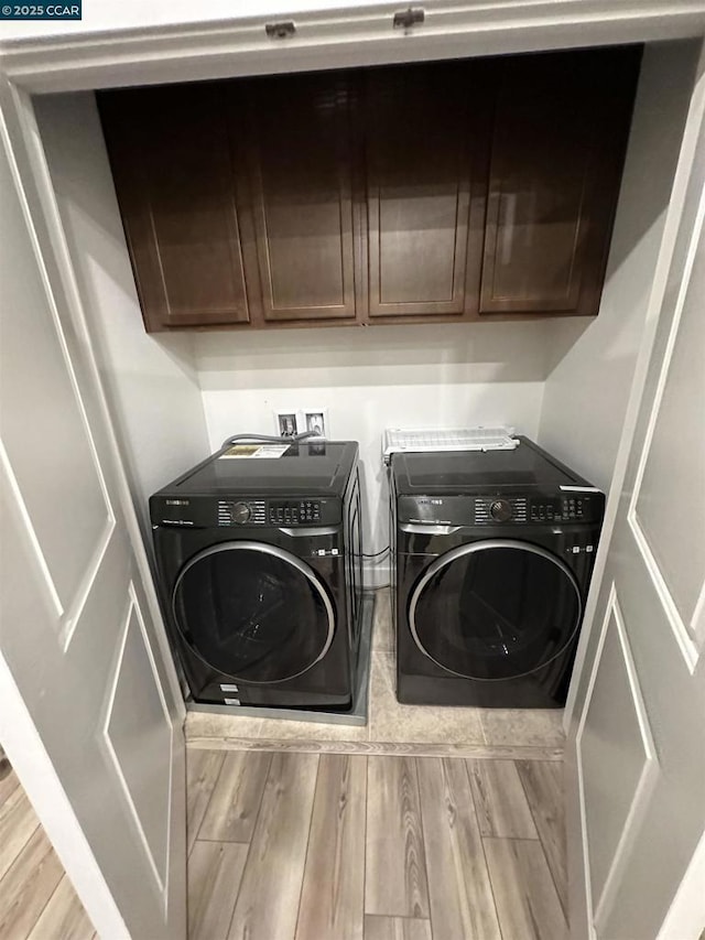 washroom with washer and clothes dryer, cabinets, and light wood-type flooring