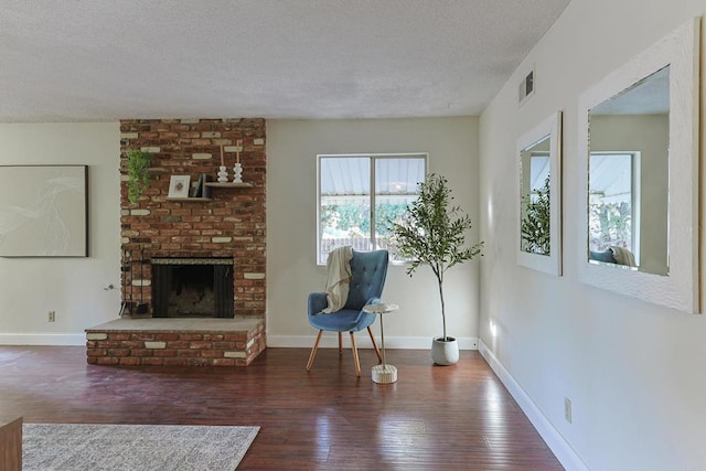 unfurnished room featuring dark wood-type flooring, a textured ceiling, and a brick fireplace