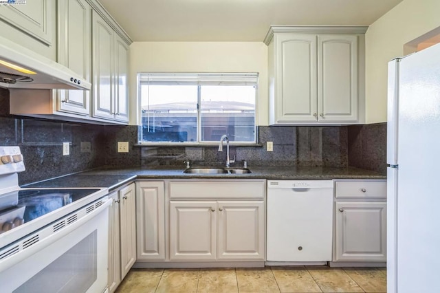 kitchen featuring light tile patterned floors, tasteful backsplash, white appliances, dark stone counters, and sink