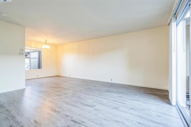 spare room featuring a notable chandelier and light hardwood / wood-style flooring