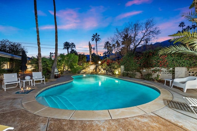 pool at dusk featuring a patio