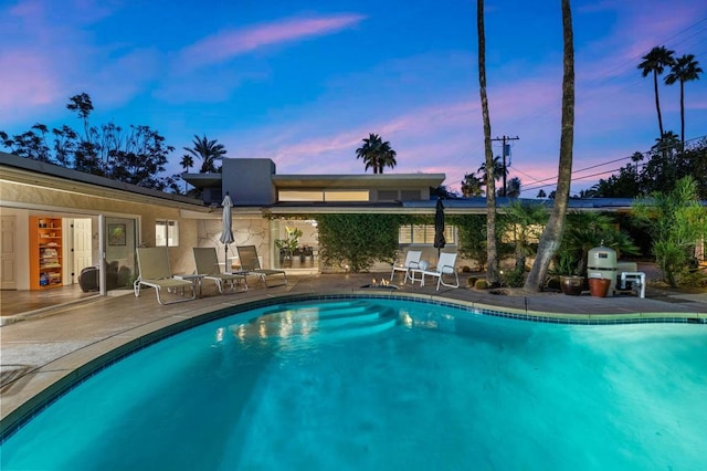 pool at dusk featuring a patio area