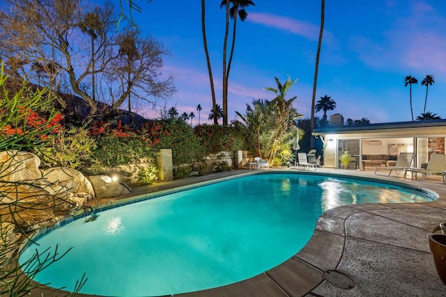 pool at dusk featuring a patio