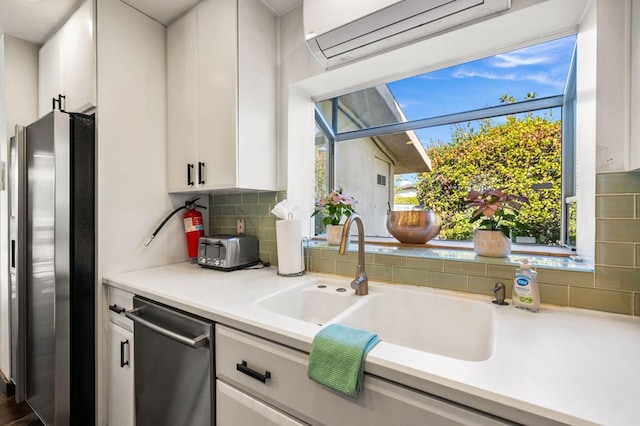 kitchen featuring an AC wall unit, backsplash, sink, stainless steel appliances, and white cabinets