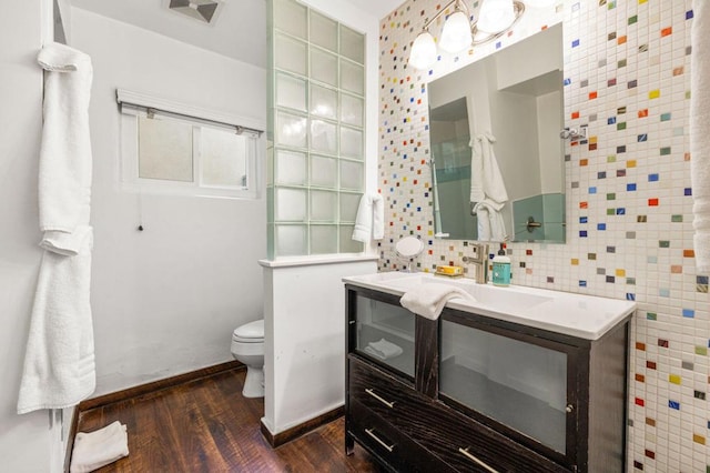 bathroom featuring toilet, decorative backsplash, wood-type flooring, and vanity