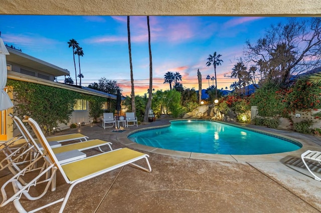 pool at dusk featuring a patio area