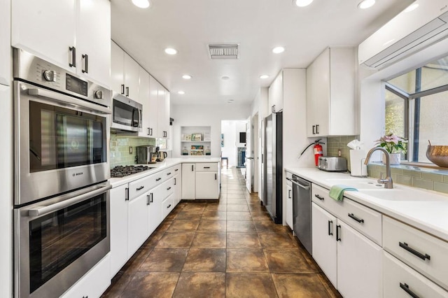 kitchen featuring backsplash, white cabinetry, appliances with stainless steel finishes, and a wall mounted air conditioner