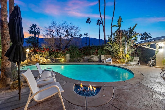 pool at dusk featuring a mountain view and a patio