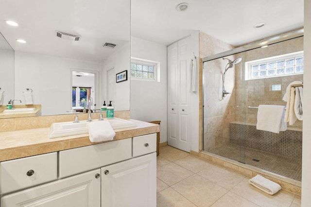 bathroom with tile patterned flooring, a shower with shower door, and vanity