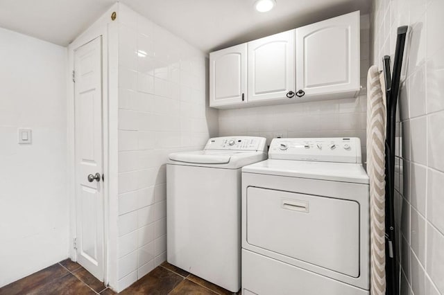 clothes washing area featuring cabinets and washing machine and clothes dryer