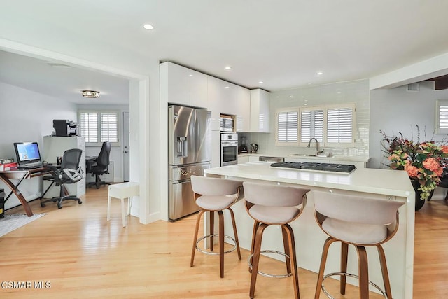 kitchen with white cabinets, a kitchen breakfast bar, stainless steel appliances, and sink