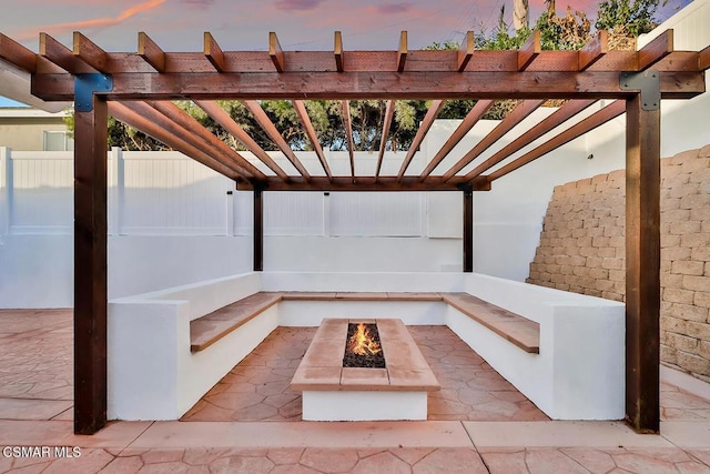 patio terrace at dusk featuring a pergola and an outdoor fire pit