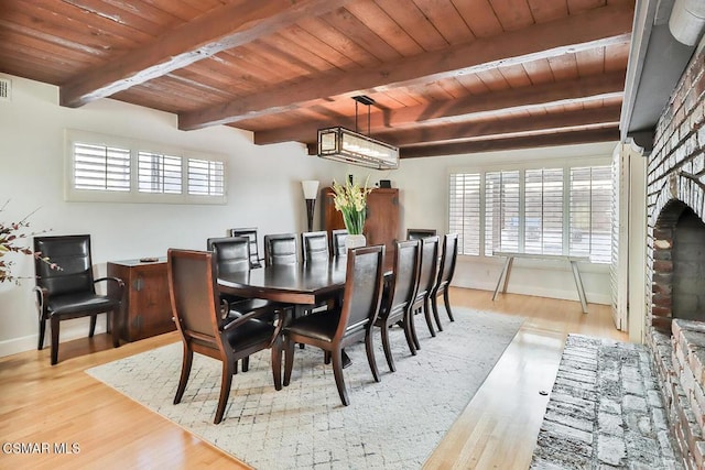 dining room featuring beamed ceiling, wood-type flooring, wood ceiling, and a brick fireplace