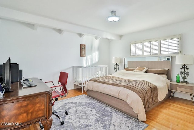 bedroom with beam ceiling and hardwood / wood-style floors