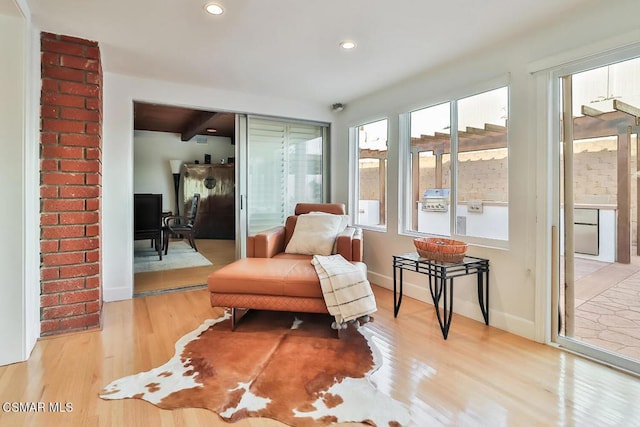 sitting room with beamed ceiling and light wood-type flooring