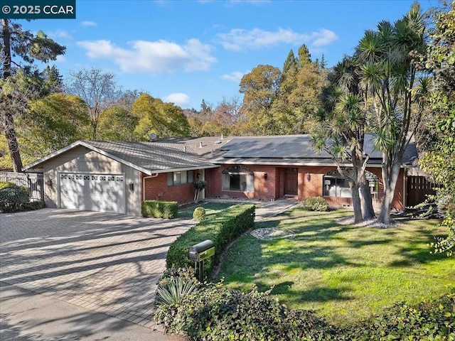 ranch-style home with solar panels, a garage, and a front lawn