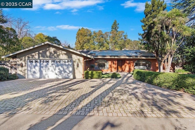 ranch-style home with solar panels and a garage