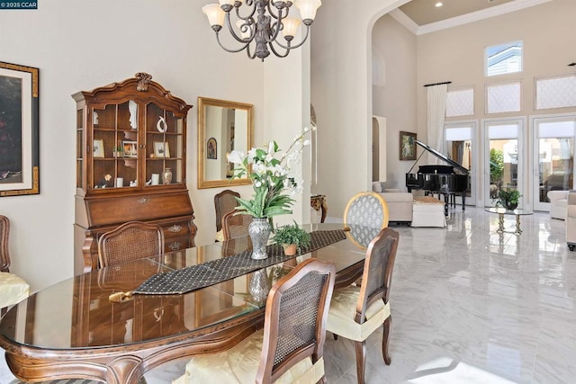 dining room featuring a towering ceiling, crown molding, and a notable chandelier