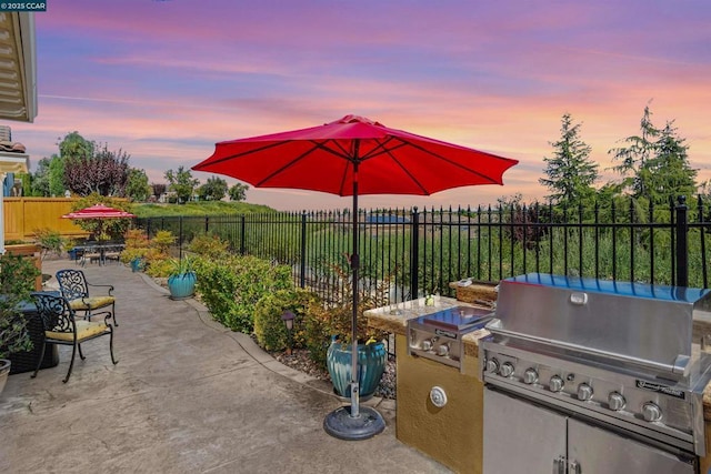 patio terrace at dusk with grilling area and an outdoor kitchen