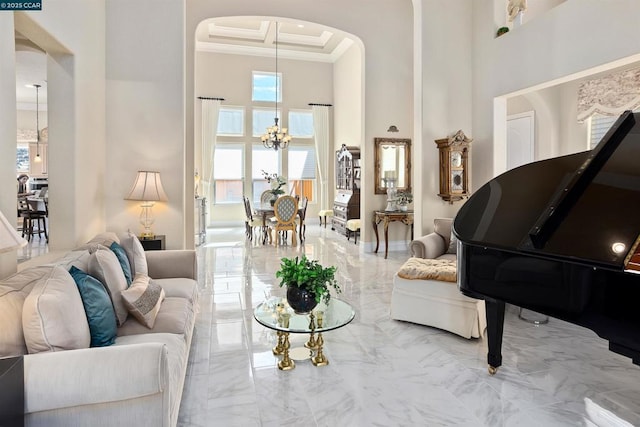 living room featuring coffered ceiling, ornamental molding, a high ceiling, and an inviting chandelier