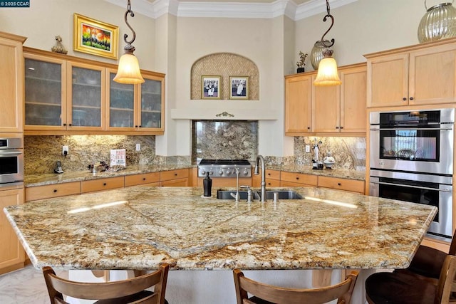 kitchen with stainless steel double oven, sink, decorative light fixtures, a center island with sink, and a breakfast bar area