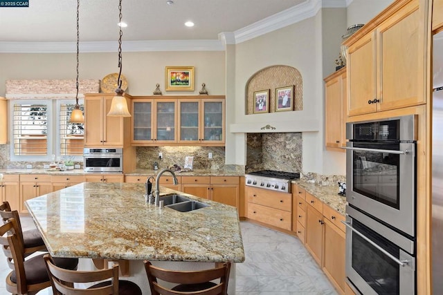 kitchen featuring appliances with stainless steel finishes, backsplash, a kitchen island with sink, sink, and light brown cabinets