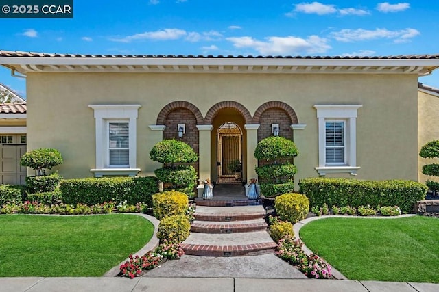 view of exterior entry featuring a lawn