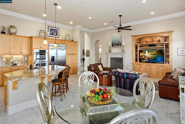 dining area featuring ceiling fan, crown molding, and sink