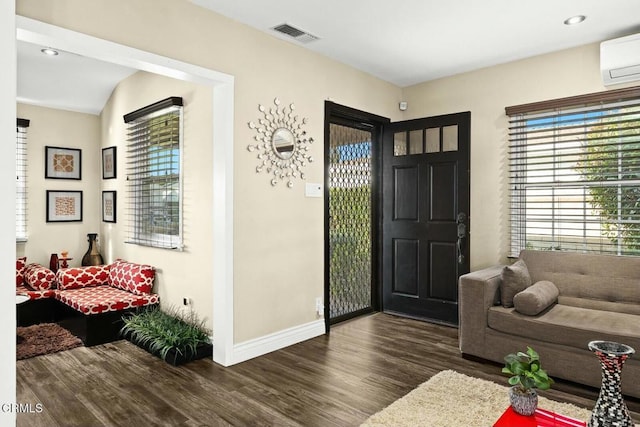 foyer with dark hardwood / wood-style floors and a wall unit AC