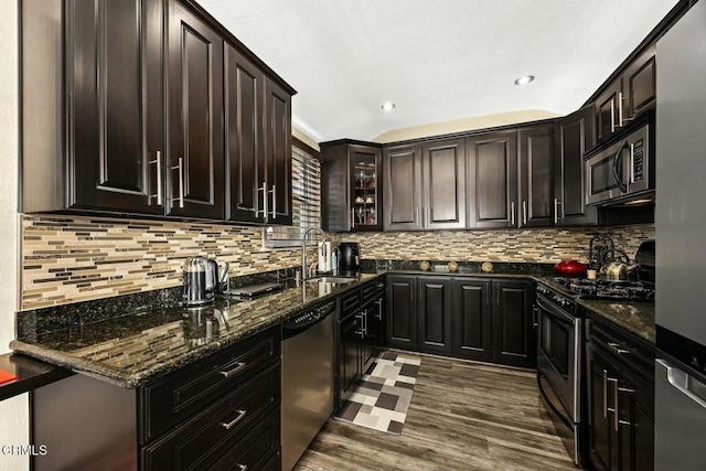 kitchen featuring sink, dark stone countertops, dark hardwood / wood-style flooring, dark brown cabinetry, and stainless steel appliances