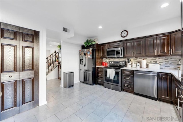 kitchen featuring light tile patterned floors, decorative backsplash, dark brown cabinets, and appliances with stainless steel finishes