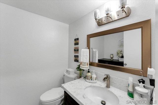 bathroom featuring vanity, a textured ceiling, and toilet