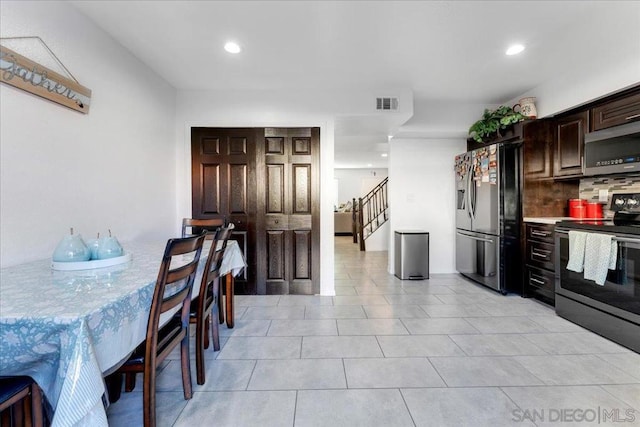 kitchen with dark brown cabinetry, light tile patterned floors, decorative backsplash, and stainless steel appliances