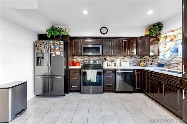 kitchen featuring appliances with stainless steel finishes, sink, decorative backsplash, light tile patterned floors, and dark brown cabinets