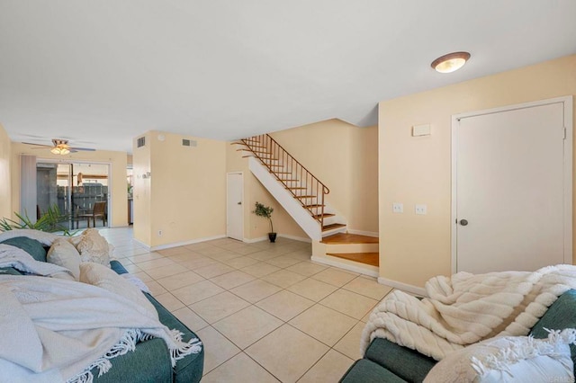 living area featuring light tile patterned floors, baseboards, visible vents, and stairway