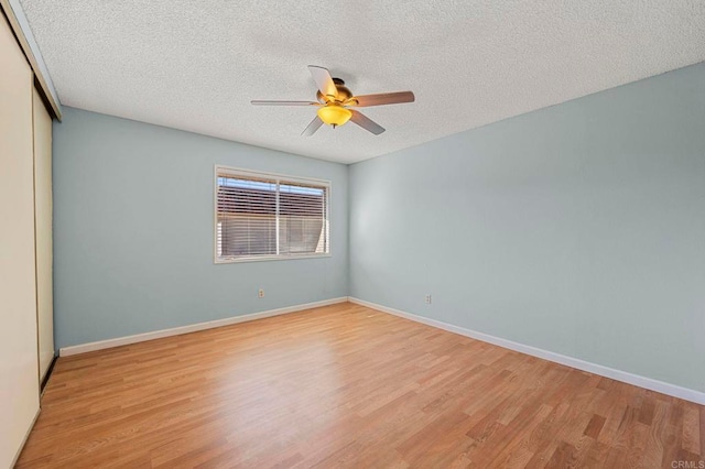 unfurnished room with light wood-style floors, a ceiling fan, baseboards, and a textured ceiling