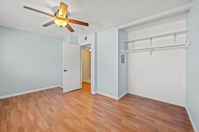 unfurnished bedroom featuring a textured ceiling, light wood finished floors, and baseboards