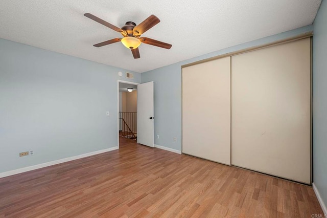 unfurnished bedroom with baseboards, light wood-style flooring, ceiling fan, a textured ceiling, and a closet