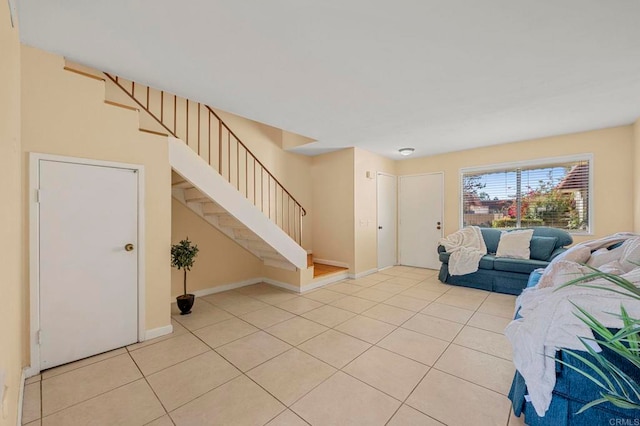 living room featuring light tile patterned floors, stairway, and baseboards