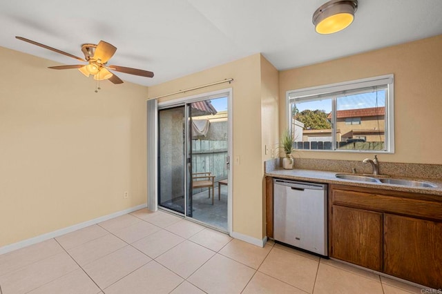 kitchen with brown cabinets, light tile patterned floors, light countertops, stainless steel dishwasher, and a sink