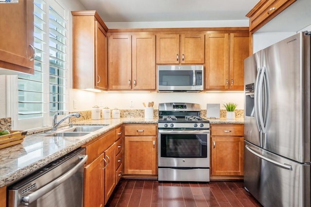 kitchen with sink, light stone countertops, and appliances with stainless steel finishes