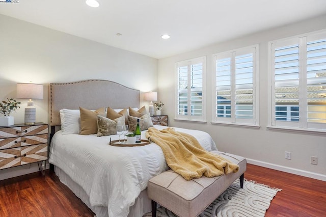 bedroom with multiple windows and dark hardwood / wood-style floors